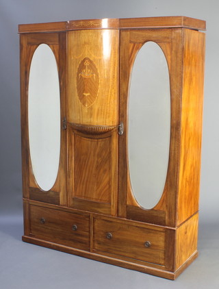 An Edwardian inlaid mahogany double wardrobe the upper section with moulded cornice, the 2 cupboards enclosed by oval bevelled plate mirrored doors, the base fitted 2 long drawers 76"h x 67 1/2"w x 20 1/2"d  