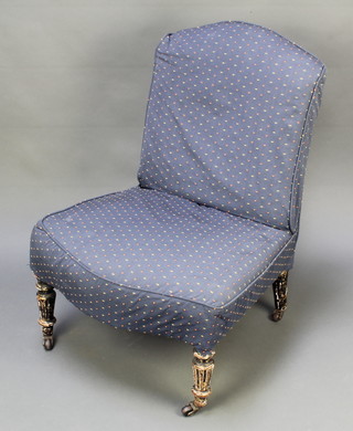 A Victorian nursing chair with blue loose cover, raised on turned and fluted supports, frame slightly loose 