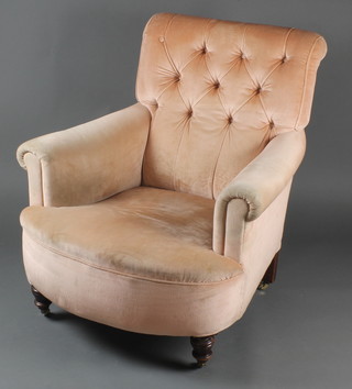 A Howard style armchair upholstered in "peach" coloured Dralon, raised on turned supports 