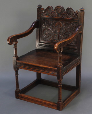 A Victorian oak open arm chair with carved panelled back and solid seat, raised on turned and block supports 