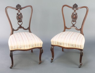 A pair of Victorian mahogany splat back salon chairs with overstuffed seats, raised on cabriole supports 