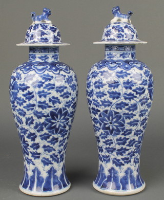 A pair of early 20th Century Chinese blue and white oviform vases and covers decorated with scrolling flowers and Shi Shi finials with 4 character marks to base 13" 