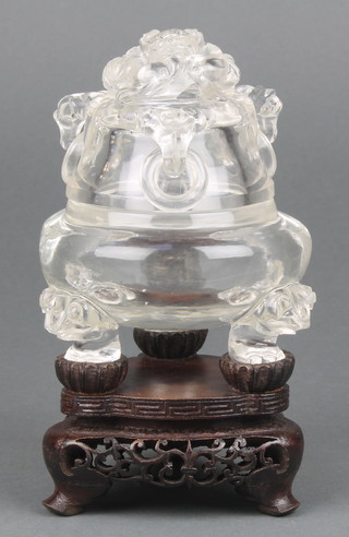 An early 20th Century well carved Chinese clear rock crystal bulbous squat censer and cover mounted by a dragon with mask drop ring handles, the base with stylised Dogs of Fo 4 1/2", raised on a carved wooden stand 
