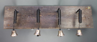 Four brass servants bells hung on a rectangular pine plank 