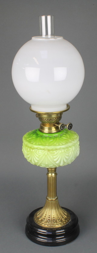 A Victorian opaque green glass oil lamp reservoir raised on a reeded gilt tapering base with opaque glass shade and clear glass chimney 