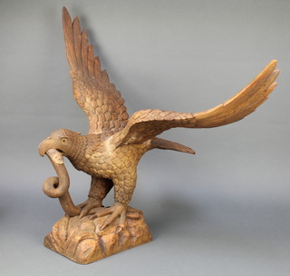 A carved wooden figure of an eagle with wings outstretched, encountering a snake, both set with hardstone eyes 28" x 34" x 23" 