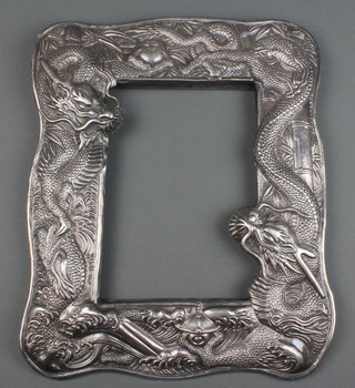 An early 20th Century Chinese repousse silver rectangular mirror frame decorated with dragons chasing the flaming pearl amongst bamboo, 723 grams, 13" x 10 1/2" 