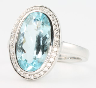 A 14ct white gold oval topaz and diamond ring, the centre stone approx. 6.5ct surrounded by approx 0.6ct of brilliant cut diamonds, size O 1/2