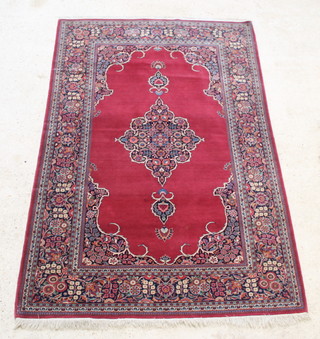 A red ground Persian rug with medallion to the centre with floral borders 82" x 53" 