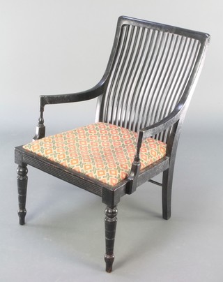 An ebonised William Morris style stick and rail back open arm chair by D Druce & Co
