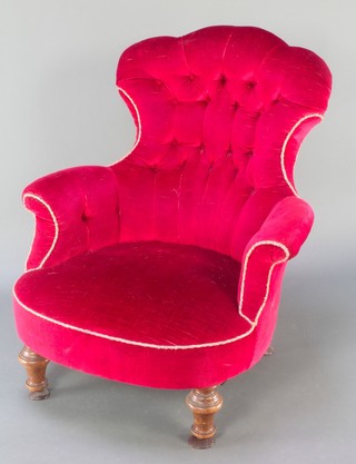 A Victorian armchair upholstered in red buttoned material on turned supports 