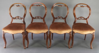 A set of 4 Victorian carved walnut balloon back dining chairs with pierced mid rails and seats of serpentine outline, raised on cabriole supports 