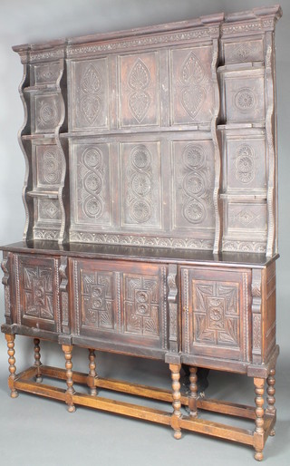 A Victorian 17th Century style carved ebonised oak dresser with associated raised back with moulded cornice, fitted various shelves, the base fitted a cupboard enclosed by panelled doors, raised on an associated base with spiral bobbin turned column and block supports 90"h x 54"w x 13"d 