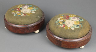 A matched pair of Victorian circular mahogany footstools with Berlin woolwork seats, raised on 3 ceramic feet 3" x 10" diam. 
