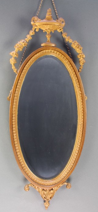 An oval bevelled plate wall mirror contained in a decorative gilt frame surmounted by a lidded urn and with garland 31"h x 12"w 