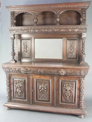 A Victorian heavily carved and ebonised oak sideboard, the associated top to the raised back with carved and moulded cornice having arcaded recess, above a mirrored panel flanked by a pair of carved panels, the base fitted 2 long drawers above triple cupboard, raised on bun feet 84"h x 66"w x 26"d 