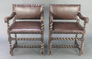 A pair of Victorian carved oak Cromwellian style open arm chairs, the seats and backs upholstered in leather, raised on spiral turned supports with H framed stretchers 