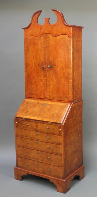 A Queen Anne style figured walnut apprentice bureau bookcase, the upper section with shaped cornice, the interior fitted shelves enclosed by panelled doors, the base with fall front revealing a well fitted interior above 2 short and 4 long graduated drawers, raised on bracket feet 38"h x 12 1/2"w x 8 1/2"d 