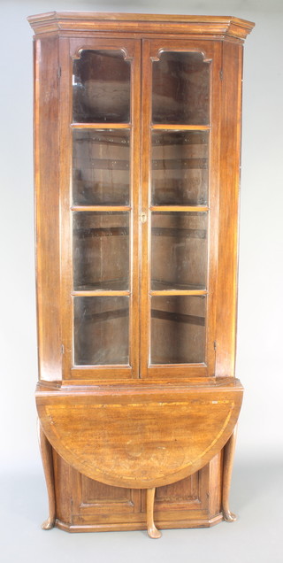 A Georgian crossbanded oak double corner cabinet the upper section with moulded cornice, fitted shelves enclosed by glazed panelled door, the base fitted a cupboard enclosed by a panelled door and having a later associated demi-lune flap fitted, 92 1/2"h x 38"w x 23"d 