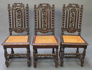 A set of 3 Victorian Carolean style high back chairs with pierced backs, the seats with woven cane panels, raised on spiral turned supports 