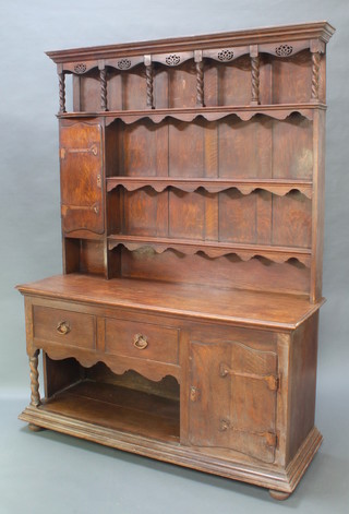 An oak Arts & Crafts dresser, the upper section with moulded and pierced cornice fitted 3 shelves flanked by a cupboard enclosed by a panelled door with planished copper hinges, the base fitted 3 long drawers above a recess flanked by a cupboard 83"h x 61 1/2"w x 20"d 