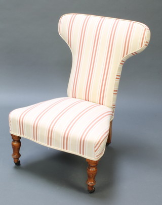 A Victorian nursing chair upholstered in striped material and raised on turned supports 