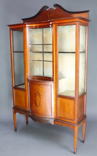 An Edwardian inlaid mahogany display cabinet the upper section with shaped raised back, the base fitted a concave and convex panel to the centre flanked by cupboards, raised on tapered supports 76"h x 44 1/2"w x 14"d 