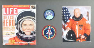 John Glenn, a signed edition of Life Magazine together with a coloured photograph, 2 circular cloth badges, framed 16 1/2" x 29 1/2" 