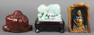 A carved hardstone figure of a seated Buddha 4" x 5 1/2" x 3", a rectangular carved hardstone panel decorated a standing Buddha 1" x 6" x 4" and a carved green hardstone figure of a sow and suckling piglets 3 1/2" x 4 1/2" x 2 1/2" 