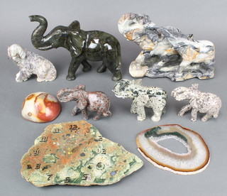 A carved hardstone figure of 2 standing elephants 8" x 11", a green hardstone figure of an elephant 7" x 10", 3 carved stone figures of elephants, a carved hardstone figure of a seated dog 4" x 6", a polished hardstone wall clock and 2 sections of polished hardstone 
