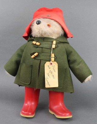 A  Paddington Bear complete with red hat and wellington boots and label 