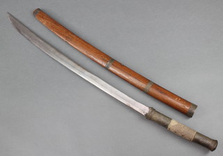 A 'Burmese" tribal sword with a 24" curved blade and metal shagreen mounted grip, contained in a wooden scabbard