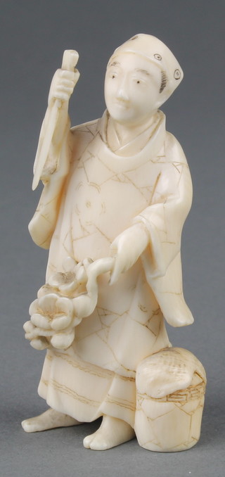 A Japanese Meiji period carved ivory okimono of a standing man holding flowers 3" 