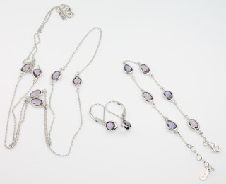 A silver necklace with purple stones together with a bracelet and pair of matching earrings