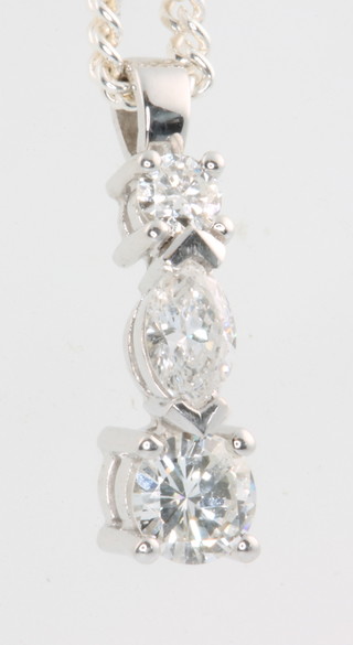 An 18ct white gold 3 stone diamond pendant, comprising 1 brilliant cut stone 0.10ct, a marquise cut stone 0.20ct and a brilliant cut stone 0.40ct, suspended on a silver chain  