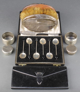 An Art Deco silver mounted leather cigarette holder London 1937, a cased set of 6 silver bean end coffee spoons, 2 napkin rings, 2 pill boxes, 2 hair brushes and a butter knife 