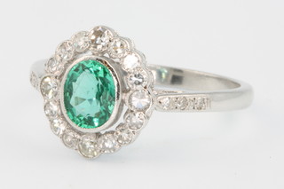 An 18ct white gold emerald and diamond oval cluster ring, the centre stone approx 0.75ct, size P
