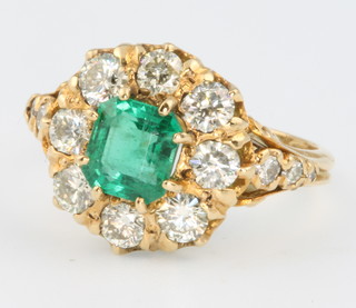 An 18ct yellow gold emerald and diamond cluster ring, the centre stone approx. 1.20ct, surrounded by diamonds approx. 1.30ct, size N