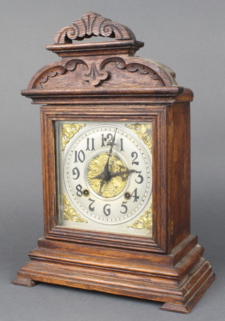 An Ansonia 8 day striking clock with silvered dial and Arabic numerals contained in an oak arch shaped case