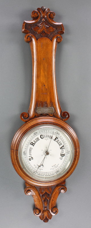 A 19th Century aneroid barometer with porcelain dial contained in a carved oak wheel case 

