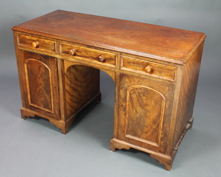 A Victorian mahogany kneehole pedestal dressing table fitted 3 short drawers with tore handles, above cupboards enclosed by arched panelled doors 29"h x 48 1/2"w x 21"d 