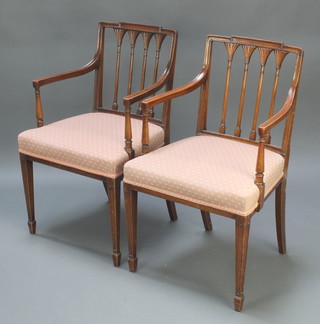 A pair of Georgian style mahogany stick and rail back carver chairs with upholstered seats raised on square tapering supports, spade feet 