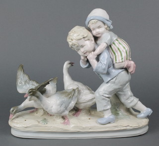 A German porcelain figure group of a boy giving a child a piggy back beside geese 12" 