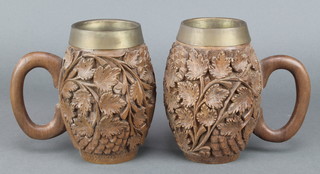 A pair of heavily carved wooden tankards decorated vinery with metal inserts 6" 
