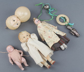 A German biscuit porcelain baby doll, the back incised 830-0 Germany 4", biscuit porcelain head and shoulders doll with fabric body 6", a "Shirley Temple" doll 7" (chips to shoes), a plated rattle with teething ring and other plastic rattles