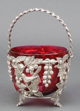 A Continental silver swing handled basket with birds, grapes and flowers having a cranberry glass liner 124 grams
