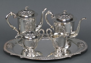 A Thai repousse silver 5 piece tea and coffee set comprising tea pot, coffee pot, milk jug, lidded sugar bowl and tray decorated with elephant finials and deities, approx. 85 ozs  