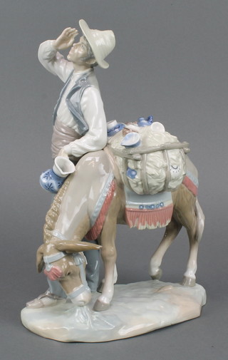 A Lladro group of a man standing beside a loaded donkey 10" 