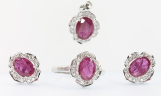 A 14ct white gold ruby and diamond suite comprising pendant, ring and ear studs, the ring size O 1/2