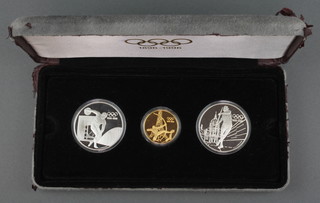 A cased 1996 Olympic commemorative coin set comprising 2 silver crowns - javelin thrower and discus thrower 7 grams and a 22ct yellow gold ditto - the archer 16.8 grams, cased 